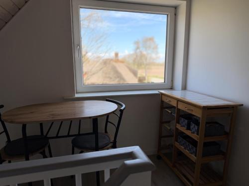 a small table and chairs in a room with a window at Harknakvej 19 BB in Bredebro
