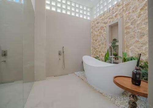 a bathroom with a white tub and a wooden table at Villa Seresa Premium- La Union in Bacnotan