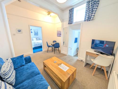 a living room with a blue couch and a table at Rose Court Holiday Apartments in Torquay