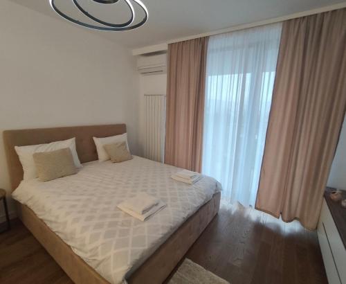 a bedroom with a bed with a large window at Komitet Planet Apartment - Free Garage & Modern stay in Niš
