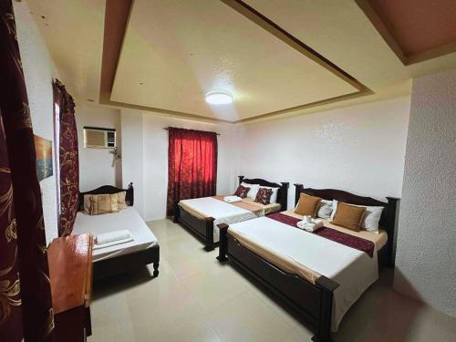ein Zimmer mit zwei Betten und einem roten Vorhang in der Unterkunft Cozy Stop Inn - Puerto Princesa in Puerto Princesa