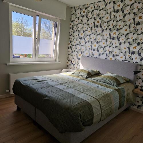 a bedroom with a bed and a wall with flowers at Vakantiewoning Duinviooltje-Koksijde in Koksijde