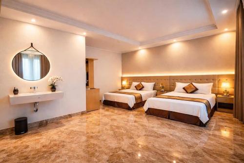 a hotel room with two beds and a sink at Serena Xuân Thành Hotel in Hà Tĩnh