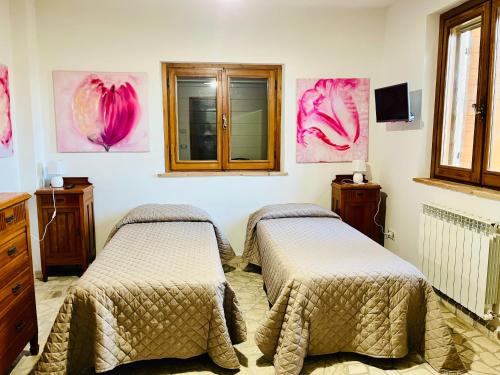 two beds in a room with pink paintings on the wall at Affittacamere La Grotta Magica in Venagrande