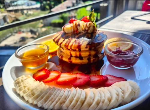 a plate of food with pancakes and fruit on a table at Niros Homestay Nuwara eliya in Nuwara Eliya