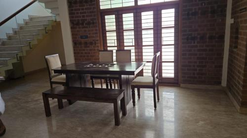 a table and chairs in a room with a brick wall at SIENNA Ecr in Chennai