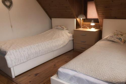 a bedroom with two beds and a dresser with a lamp at Domek Eve in Giżycko