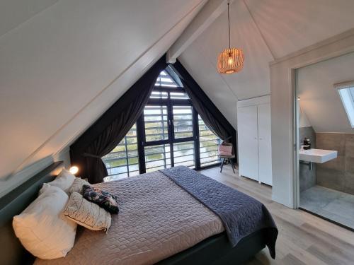 a bedroom with a large bed with a large window at Lutz Watervilla's Balk in Balk