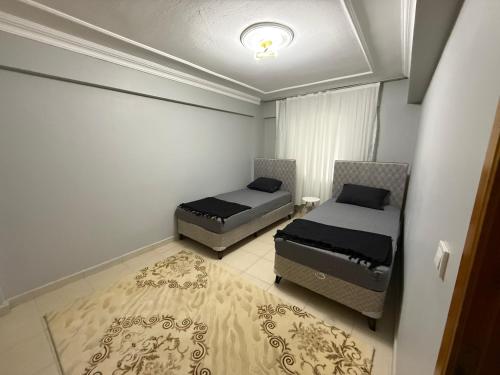 a bedroom with two beds and a rug at Liva Konukevi in Ayvalık