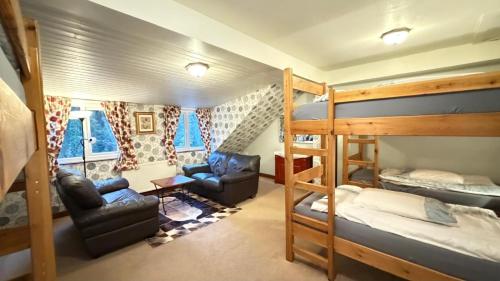 a dorm room with bunk beds and a couch and chairs at Lledr House Hostel near two Zip World sites in Dolwyddelan