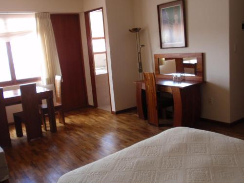a bedroom with a bed and a desk and a mirror at Hotel Villa Antigua in Sucre