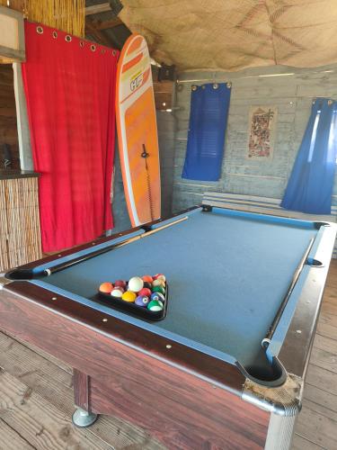 a pool table with balls on it next to a surfboard at Espace baleine Anakao in Anakao