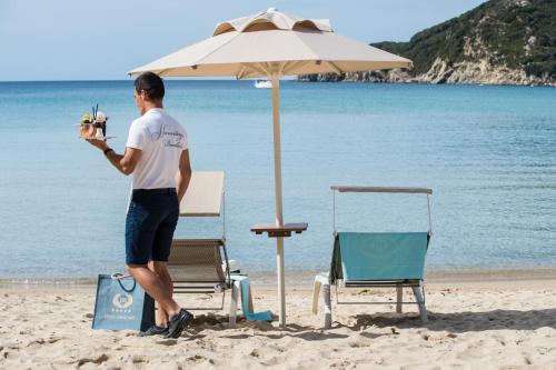 a man standing under an umbrella on the beach at Hotel Hermitage in Portoferraio