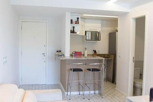 a kitchen with a counter and two bar stools at Camboinhas Oceanside Oceanfront in Rio de Janeiro
