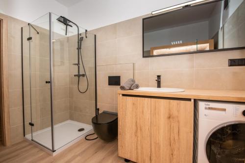 a bathroom with a shower and a sink and a washing machine at Apartmán Istebné luxure in Istebné