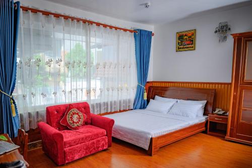 a bedroom with a bed and a red chair at Diamond Suite Dai Nam Hotel in Can Tho