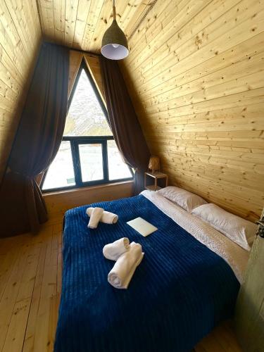 a bedroom with towels on a blue bed with a window at Take A Brake Kazbegi Cottage in Kazbegi