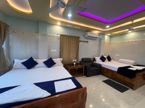 a bedroom with two beds and a chair in it at Hotel Raj in mayapur