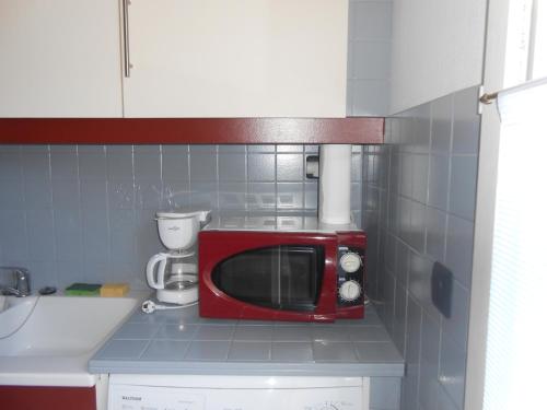 a red microwave sitting on top of a kitchen counter at Herault Maraussan in Maraussan