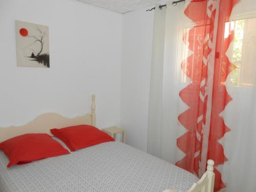 a bedroom with a bed with a red pillow and a window at Herault Maraussan in Maraussan