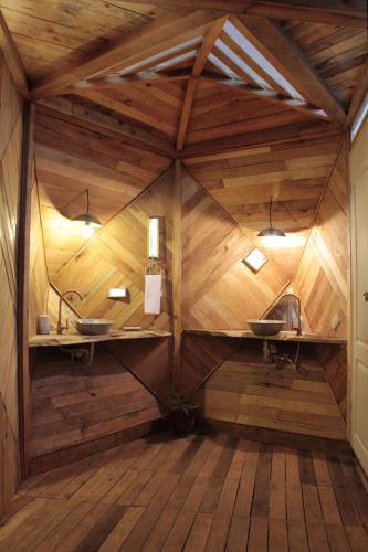 a bathroom with two sinks in a wooden wall at Caracolito Hostal in Las Peñitas