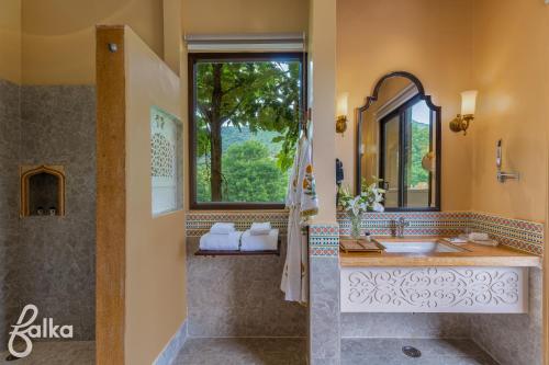 a bathroom with a sink and a mirror and a window at Dev Bagh Luxurious Private Suites in Debāri