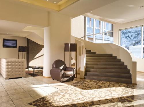 a living room with a staircase and a chair at Grand Hotel Paradiso in Passo del Tonale