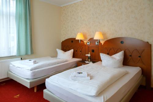 a hotel room with two beds and a window at Hotel Goldener Fasan in Oranienbaum-Wörlitz