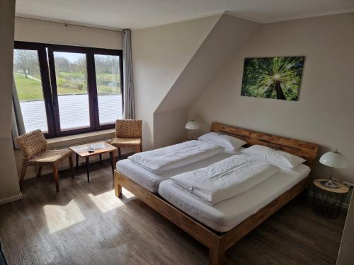 a bedroom with a large bed and two chairs at Pension zur Schleuse GARNI am Elbe Lübeck - Kanal in Witzeeze in Witzeeze