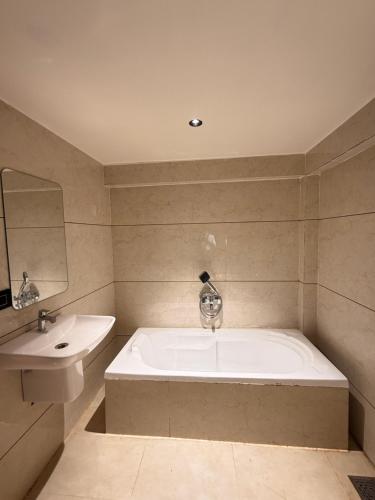 a bathroom with a large tub and a sink at Hotel Presidency - Sosyo Circle in Surat