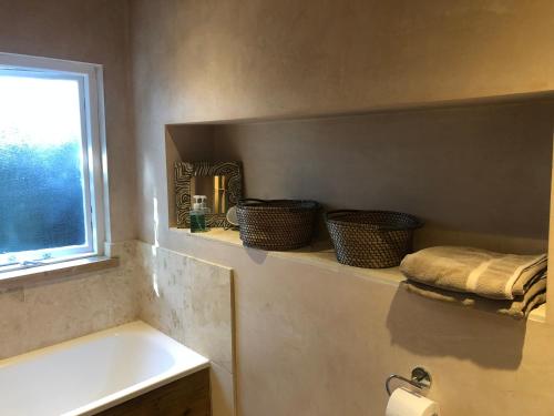 a bathroom with a sink and baskets on a shelf at Artistic spacious flat in central Brixton in London