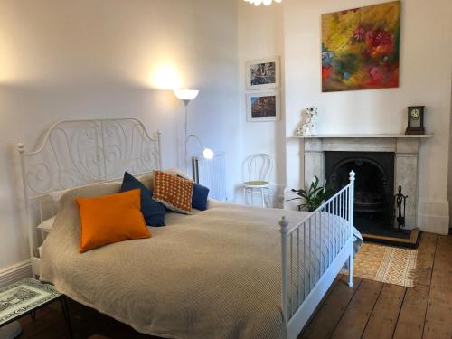 a bedroom with a bed with orange pillows and a fireplace at Artistic spacious flat in central Brixton in London