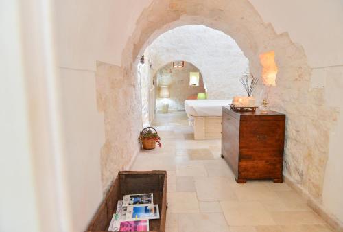 a bedroom with an archway with a bed and a table at Trullo L'alcova in San Vito dei Normanni