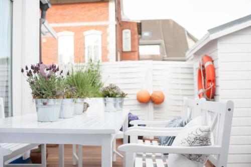 een witte tafel en stoelen op een veranda met planten bij Boutique Hotel Haus Noge Sylt - Kapitaenshaus strandnah in Westerland
