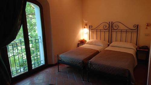 two beds in a room with two large windows at Campastrello Sport Hotel Residence in Castagneto Carducci