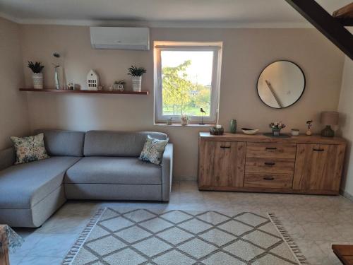 a living room with a couch and a mirror at Tóthék Apartman in Szigetvár