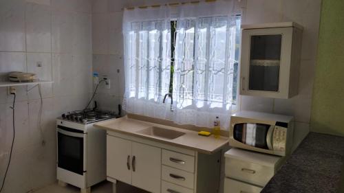 a small kitchen with a sink and a microwave at Cabana in Santo Antônio do Pinhal