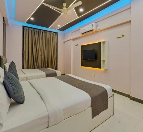 two beds in a hotel room with a tv at Majestic Royal by Travel Pleasure Hotels in Akalkot