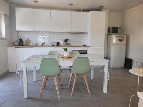 a kitchen with a white table and green chairs at Oeiras Historic Bedrooms in Oeiras