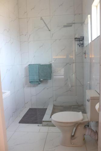 a white bathroom with a toilet and a shower at Townside Estate Room number 10 in Ladysmith