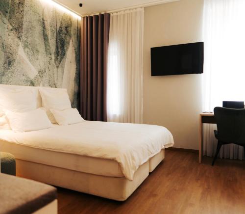 a hotel room with a bed and a television at The Kepos Hotel Erlangen in Erlangen