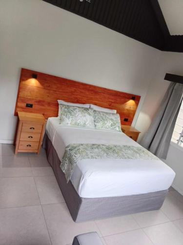 a bedroom with a large bed and a wooden headboard at Savusavu Terraces - Unit 3 in Savusavu