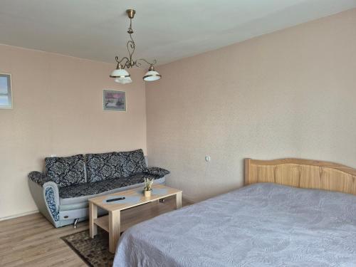 a bedroom with a bed and a couch and a table at Sunrise in Rēzekne