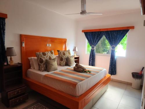a bedroom with a bed with blue curtains and a window at Villa Admiral in Praslin