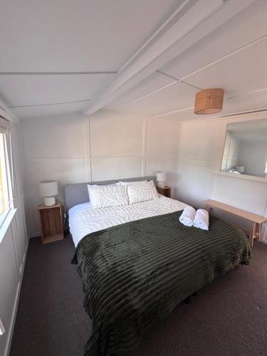 a bedroom with a large bed with two towels on it at Pine Cottage in Dennes Point