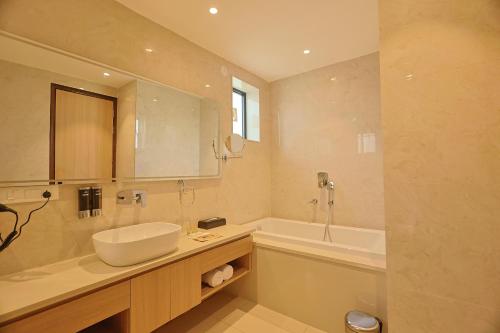 a bathroom with a sink and a tub and a mirror at Pride Premier Alwar - Sariska in Alwar
