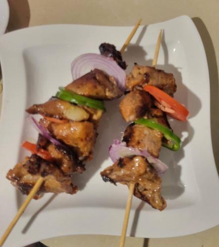 a plate of food with chicken skewers and vegetables at Philo Leisure Gardens in Kalangala