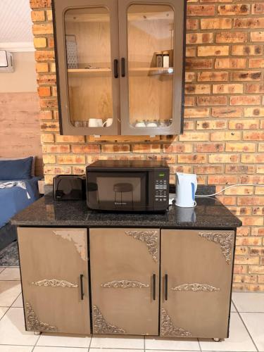 a microwave on a counter in a kitchen with a brick wall at On Smook in Zeerust