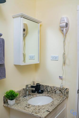 a bathroom with a sink and a hair dryer at Colbeck sunshine oasis in Old Harbour