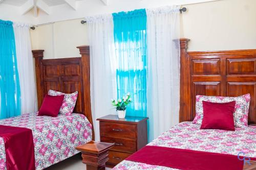 a bedroom with two beds and blue curtains at Colbeck sunshine oasis in Old Harbour